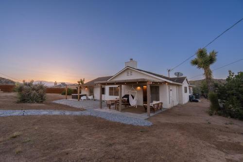 a small white house with a sunset in the background at License To Chill in Yucca Valley