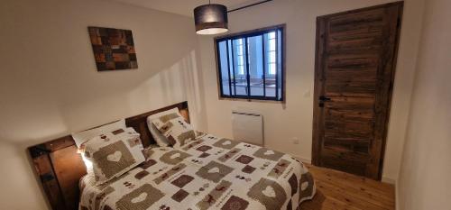 une chambre avec un lit avec une couette et une fenêtre dans l'établissement Le cosy du Théâtre, duplex confortable au centre de Chambéry, à Chambéry