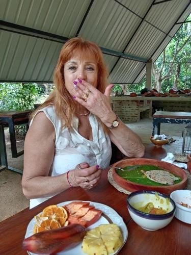 a woman sitting at a table with a plate of food at Dambulla Tree House in Dambulla