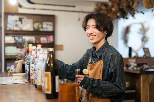a man standing at a counter with a bottle of wine at Guest House Waya in Sapporo
