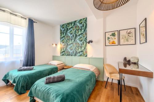 two beds in a room with a table and a window at Maison 8 pers plein centre ville in Lesneven