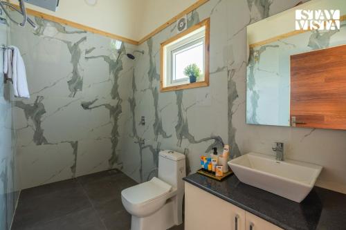 un baño con inodoro y lavabo en StayVista at Aarna Estate with library, lawn, en Tāoru
