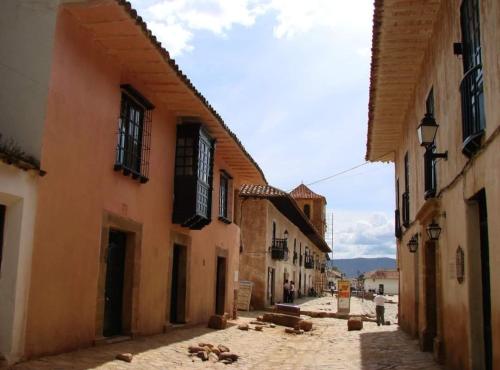 an alley with buildings and animals laying on the street at villa sandaned in Villa de Leyva