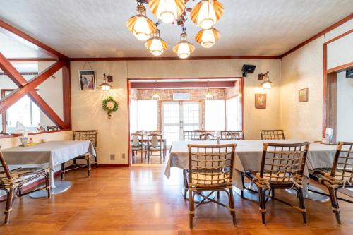 a dining room with tables and chairs and a chandelier at Pension Bonnard in Hakuba