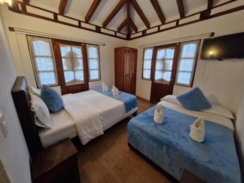 a bedroom with two beds with blue pillows at villa sandaned in Villa de Leyva