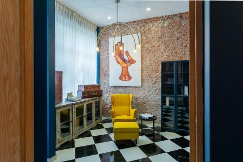 a room with a yellow chair and a checkered floor at Chihuahua Boutique Centric Studio & Loft in Mexico City