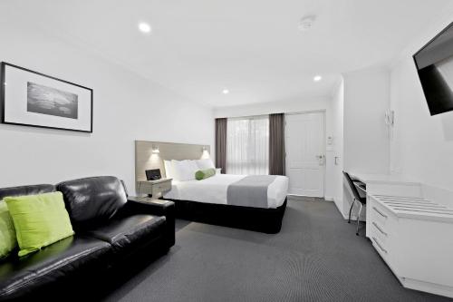 a hotel room with a bed and a couch at Hamilton Lonsdale Motel in Hamilton