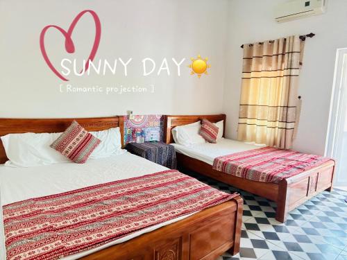 a bedroom with two beds and a sign that reads sunny day at Cô Tô Lương Chi in Quang Ninh