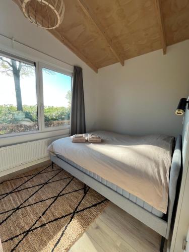 a bed in a room with a large window at Ruimte, privacy en comfort op de Veluwe, inclusief 2 fietsen & linnengoed in Nunspeet