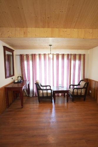un soggiorno con due sedie e un tavolo di Hotel Monal a Manāli