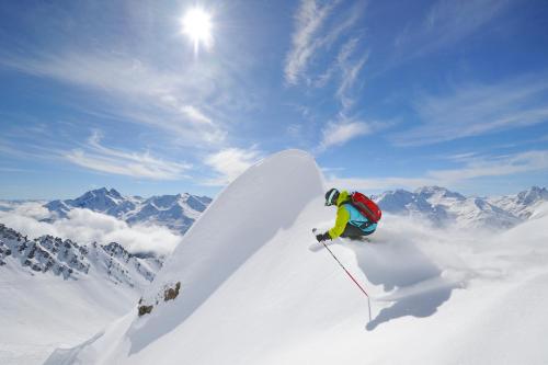 a man riding a snowboard down a snow covered slope at Haus Anna Apartments in Langen am Arlberg
