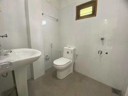 a white bathroom with a toilet and a sink at Travel Lodge City Hotel in Trincomalee