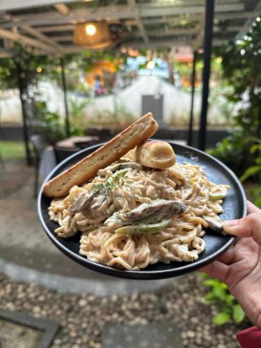 a person holding a plate of food with noodles at Fernando's Hotel in Sorsogon