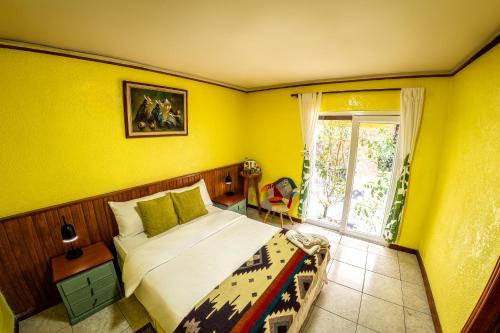 a yellow bedroom with a bed and a window at La Casa del Molino Blanco B&B in Baños