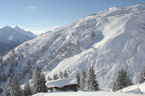 a mountain covered in snow with a cabin in the foreground at Haus Anna Apartments in Langen am Arlberg