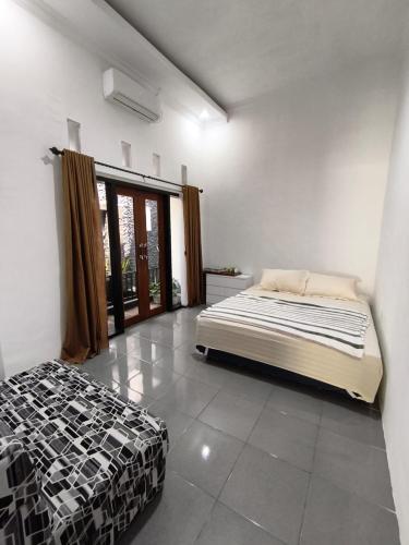 バニュワンギにあるnadien home stay Banyuwangiのベッドと大きな窓のある寝室