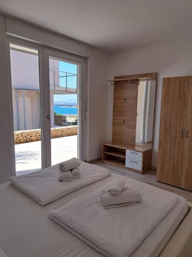 a bedroom with two beds and a large window at Novaedil Apartment in Povljana