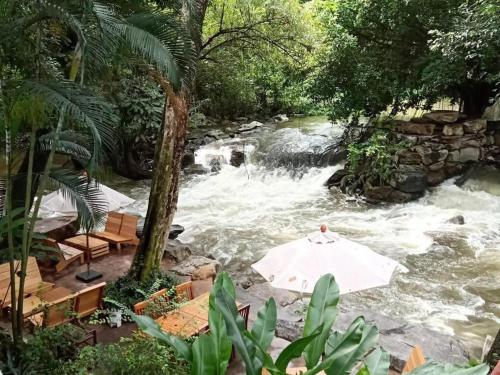 an umbrella in front of a river with rapids at khaoyai lumtakong hotel in Mu Si
