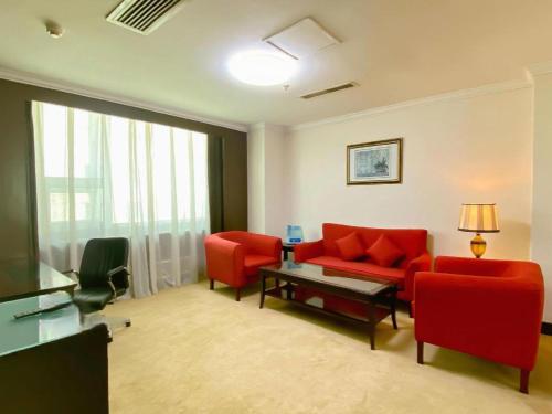 a living room with red chairs and a red couch at Changchun Zhuozhan Days Hotel in Changchun