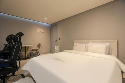 a bedroom with a large white bed and a black chair at Chuncheon World Hotel in Chuncheon
