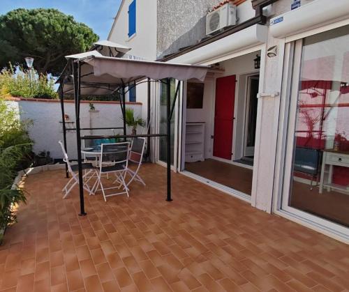 d'une terrasse avec un auvent, une table et des chaises. dans l'établissement Les Patios de Toreilles, douce parenthèse, à Torreilles