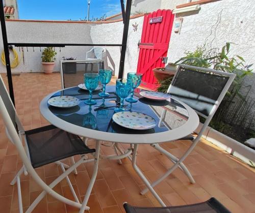une table avec des verres bleus et deux chaises sur une terrasse dans l'établissement Les Patios de Toreilles, douce parenthèse, à Torreilles