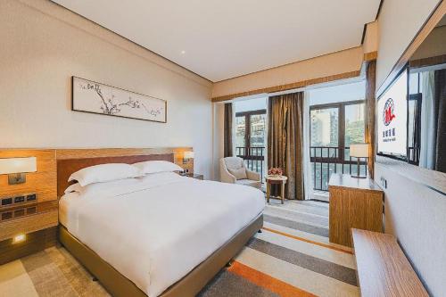 a hotel room with a bed and a large window at MeiQiu-Fino Hotel in Zhuhai