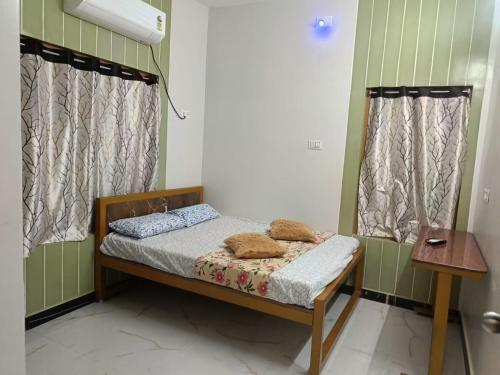 a small bed in a room with two windows at Little Hearts recidency in Āvadi