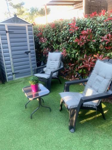 two chairs and a table in a yard at mobilhome 3 chambres camping boisé in Nans-les-Pins