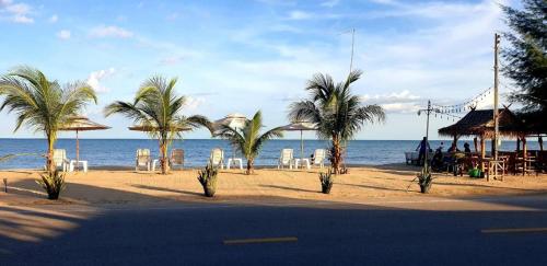 a beach with palm trees and chairs and the ocean at Seascape Resort Baan Krood in Ban Krut