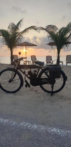 a bike parked on the beach with the sunset at Seascape Resort Baan Krood in Ban Krut