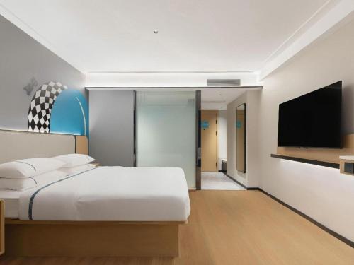 a bedroom with a bed and a flat screen tv at City Comfort Inn Wuhan Hankou Railway Station West Square in Wuhan