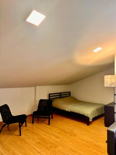 a bedroom with a bed and two chairs in it at Perlos Apartamentai 13 in Birštonas
