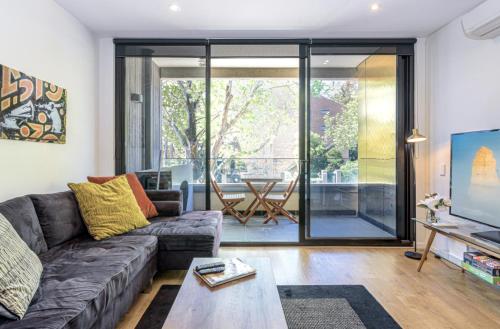 a living room with a couch and a table at Cosmo Stays- Designer Apartment Fabulous Location in Melbourne
