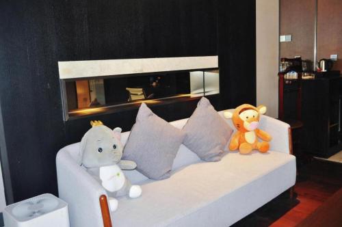 two stuffed animals sitting on a bed in a room at NH Shijiazhuang Financial Center in Shijiazhuang