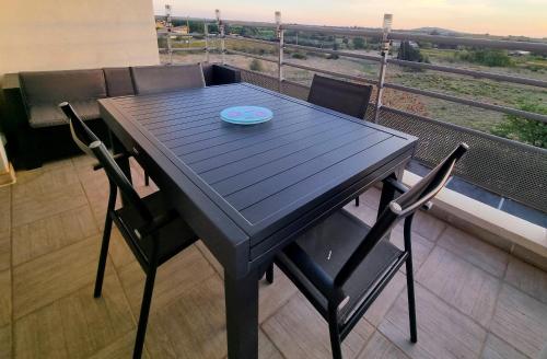 une table noire avec deux chaises et une plaque de cuisson dans l'établissement Chambre chez l'habitant, à Marseillan
