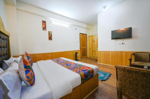 a bedroom with a bed and a flat screen tv at FabHotel Paradise Guest House in Kyelang