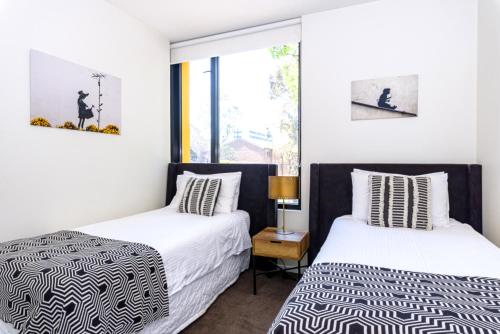 two beds in a room with white walls at Cosmo Stays- Designer Apartment Fabulous Location in Melbourne