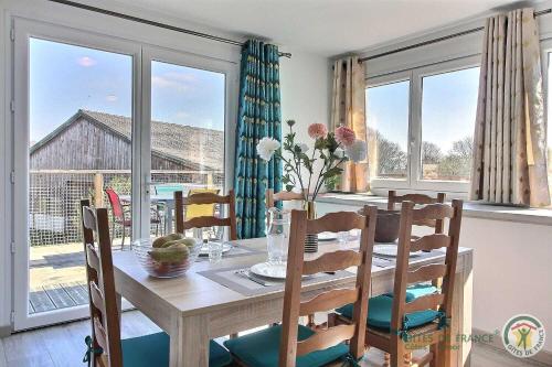 une salle à manger avec une table, des chaises et des fenêtres dans l'établissement Le nid d'hirondelles, à Bourbriac