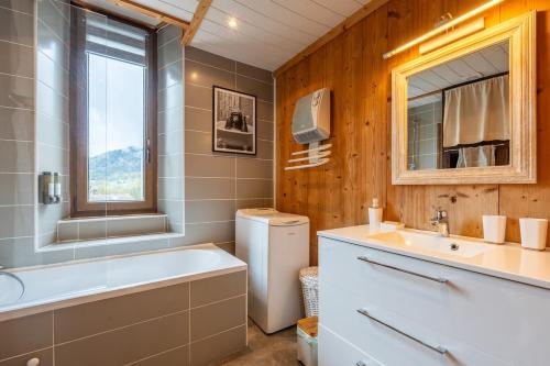 La salle de bains est pourvue d'une baignoire blanche, d'un lavabo et d'un lavabo. dans l'établissement Havre de paix entre Lac d'Annecy & Montagnes, à Alex