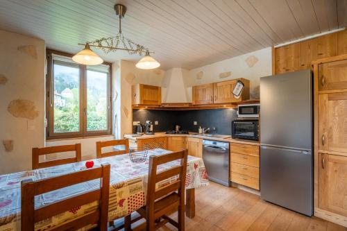 une cuisine avec une table et un réfrigérateur dans l'établissement Havre de paix entre Lac d'Annecy & Montagnes, à Alex