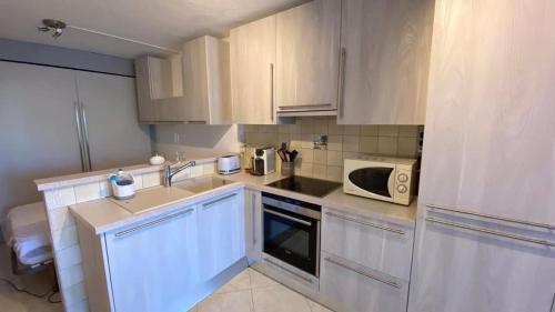 une cuisine avec des armoires blanches et un micro-ondes dans l'établissement Studio Arc-en-ciel, à Sète
