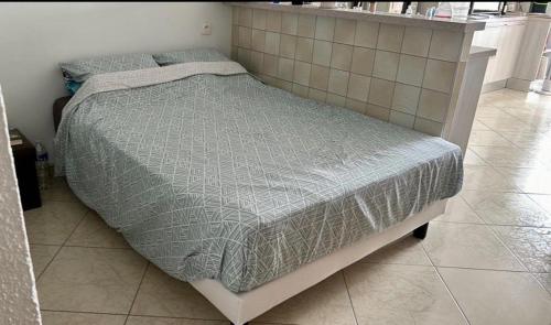 - un lit avec une couette grise dans l'établissement Studio Arc-en-ciel, à Sète