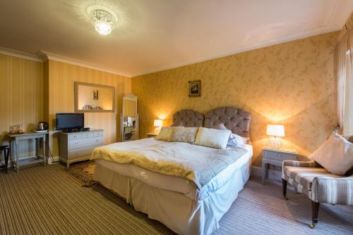 a bedroom with a large bed and a television at Maenan Abbey Hotel in Llanrwst