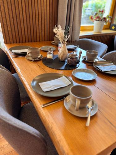 a wooden table with plates and utensils on it at Pension Bavaria in Mittenwald