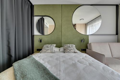 a bedroom with a large bed and two mirrors at GRANO APARTHOTEL Ustronie Morskie in Ustronie Morskie