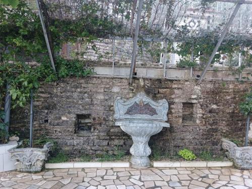 a stone fountain in front of a brick wall at Guest House Bake in Gjirokastër