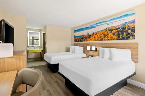 a hotel room with two beds and a desk at Days Inn by Wyndham Petersburg/South Fort Lee in Petersburg