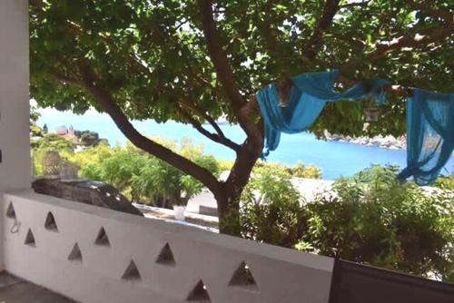 a white fence with a tree and a swimming pool at Kythnos Aegean Bliss - Kanala Seaview Getaway in Kanala