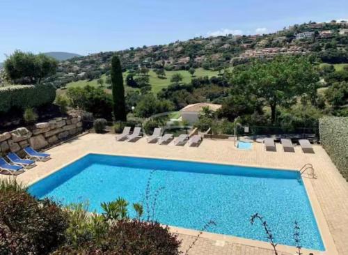- une piscine avec des chaises et une vue sur une colline dans l'établissement Villa nichée sur golf & piscine, à Sainte-Maxime